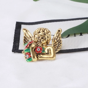 Detail of vintage angel brooch with red enamel flowers and sparkling rhinestones