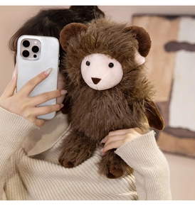 Close-up of a dark brown plush sheep toy with brown horns held by a model in a cozy setting