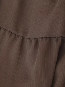 Macro detail of dark brown textured fabric with pleated seams and sequin embroidery accents