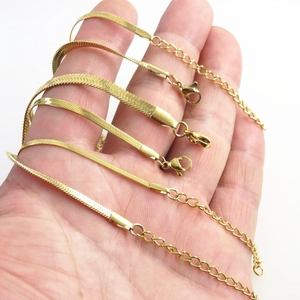 Detail of multiple gold stainless steel snake chains with lobster clasps and tags