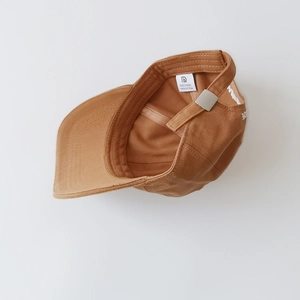 Detail view of cotton baseball cap showing adjustable metal buckle and interior labels