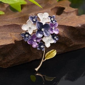 Detail of floral enamel brooch with daisy patterns, crystal centers and gold stem