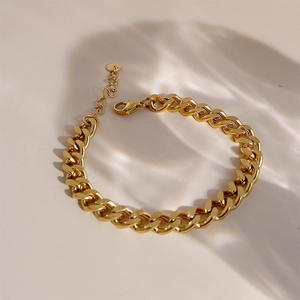 Gros plan d'un bracelet à gros maillons dorés avec fermoir mousqueton et chaînette