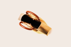 Top-down detail of gold crocodile texture handbag with brown curved handles and black lining