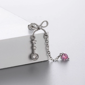 Silver bow and key earrings with pink heart pendant and clear crystals on a white pedestal