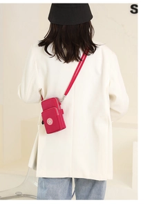 Rear view of model wearing a rose red nylon vertical crossbody phone bag with two zippers