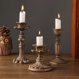 Set of three vintage resin candle holders with lit pillars on a dark wooden table