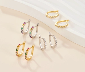 Macro detail of U-shaped silver hoop earrings with 925 hallmarks and colorful zircons