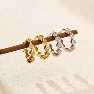 Detail of gold and silver S925 geometric rhombus hoop earrings with zircon stones on a branch