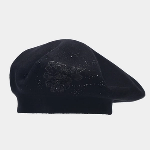 Dettaglio di applique floreale in pizzo e strass sulla berretta in maglia nera