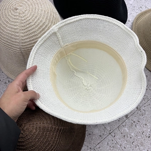 Detail of white knit bucket hat showing internal sweatband and adjustable drawstring feature