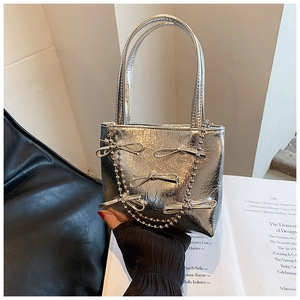 Detail of silver handbag with metallic texture, bow beaded strap, and chic handle
