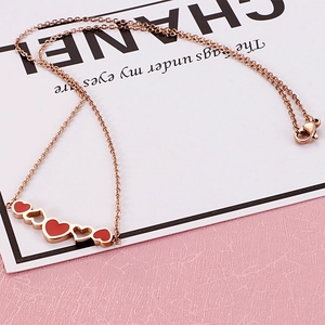 Detailed view of women's heart necklace with red enamel and rose gold hollow charms