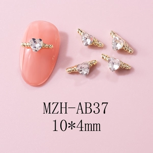 Macro shot of 10x4mm gold heart nail charms with wings on pink manicured nails