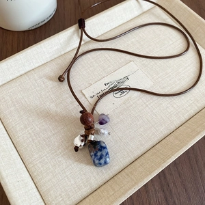 Detailed close-up of ethnic necklace with blue stone, wood bead, and natural pearl