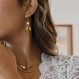Detail of 18K gold stainless steel fringe earrings and layered pearl necklace on model