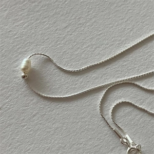 Macro shot of 925 sterling silver chain with elegant freshwater pearl and silver bead