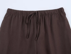 Detail of dark brown cotton linen trousers with elastic drawstring waistband and texture