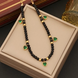 Stainless steel necklace with emerald heart pendants and black beads in a jewelry box