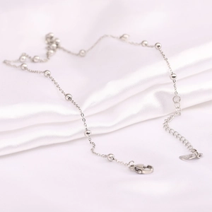 Detail of silver stainless steel bead chain with lobster clasp on white silk background