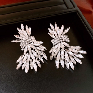 Détail de boucles d'oreilles ailes en argent avec cristaux brillants sur plateau noir