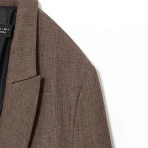 Gros plan sur un blazer marron en maille montrant les coutures du col et l'étiquette MEX 30