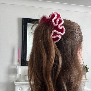 Detailed back view of a person wearing a red and pink crochet ruffle hair scrunchie