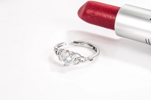 Detailed close-up of S925 sterling silver heart ring with white zircon beside a red lipstick