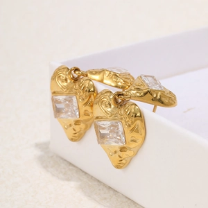 Detail of vintage gold heart earrings with hammered texture and clear square zircon
