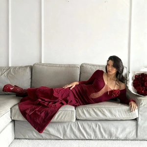 Robe longue vintage en velours rouge avec roses 3D et détails ajourés sur un canapé
