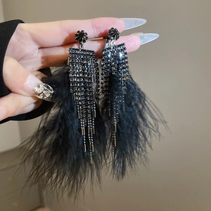 Detail shot of black rhinestone feather tassel earrings featuring sleek dark metal fringe