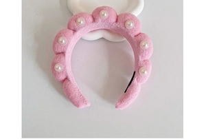 Close-up of pink fluffy sponge headband with elegant white pearl decorations on white background