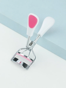 Detail of mini stainless steel eyelash curler with pink silicone pad and white handle