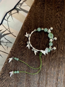 Detailed shot of bamboo-style silver bracelet with butterfly charms and green beads