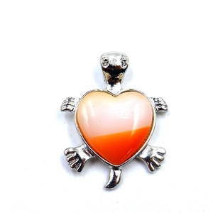Detail van een zilveren schildpad hanger met een hartvormig oranje kristal op witte basis