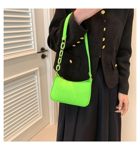 Detail of neon green crocodile texture handbag with gold hardware and chain strap