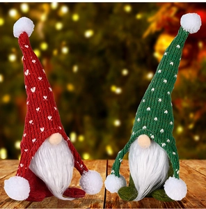 Detail von roten und grünen gestrickten Weihnachtswichteln mit weißen Bärten auf Holz