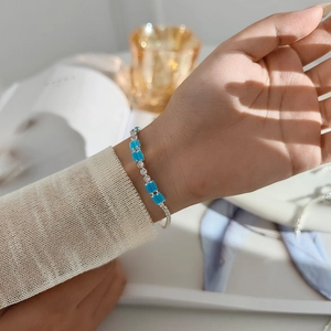 Detailed close-up of a silver clasp bracelet with sky blue stones and zircon inlay