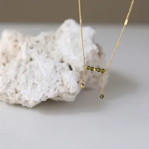 Golden titanium steel necklace featuring olive green crystals and a tassel pendant design