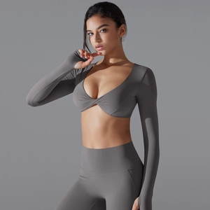 Dettaglio del top da yoga grigio a maniche lunghe con nodo a torsione e leggings a vita alta
