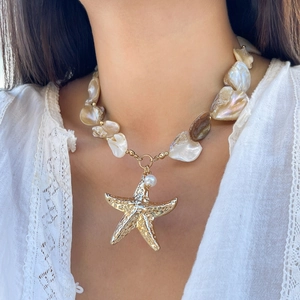 Detail shot of a pearl beach necklace with a gold starfish pendant on a female model