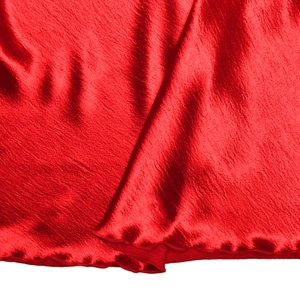 Gros plan du tissu satiné rouge avec finition brillante et bordures ourlées