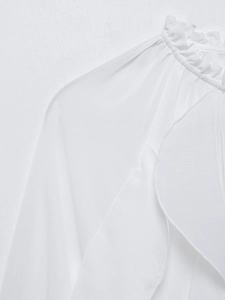 Detail view of the ruffled high collar and textured chiffon fabric on the white blouse