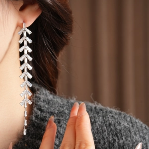 Detail of silver long tassel earrings with baguette cut zircon v-shaped layering