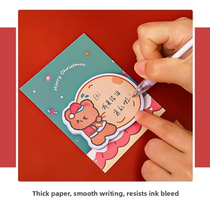 Close-up of a bear-shaped Christmas sticky note with a Santa hat being written on