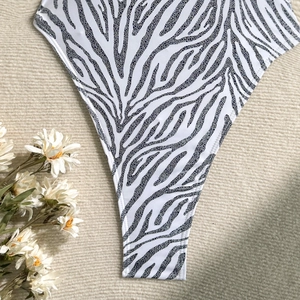 Detailed view of gold foil zebra print swimwear fabric with high-cut leg opening