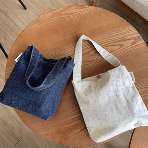 Close-up of denim and cream canvas tote bags with magnetic clasp and woven label details