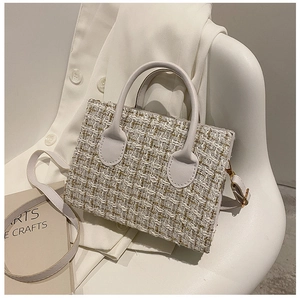 Detailed close-up of cream tweed woven handbag with golden texture and leather handle