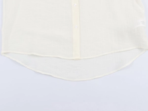 Detailed macro view of the beige textured fabric shirt with buttons and curved hem