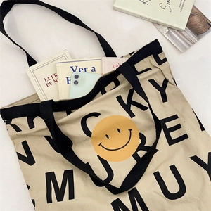 Flat lay of canvas tote bag with smiley face print, featuring books and a smartphone